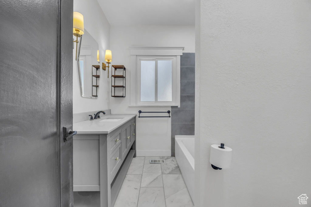 Bathroom with marble look tiles, vanity, a tub, and a shower