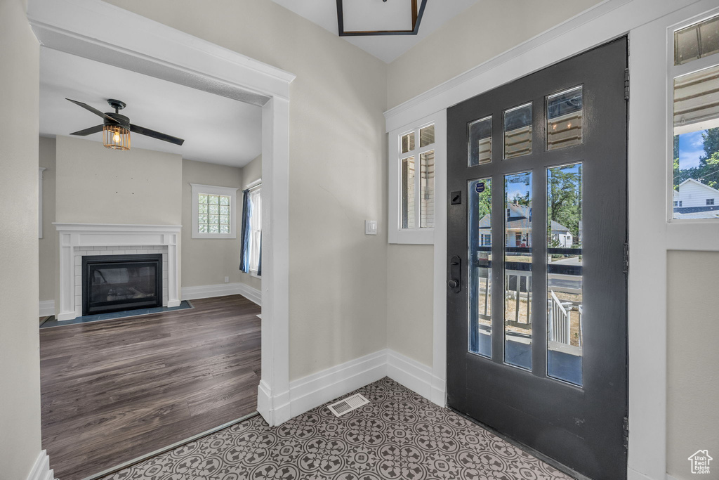 Entrance foyer with a ceiling fan, a fireplace with flush hearth, and wood finished floors