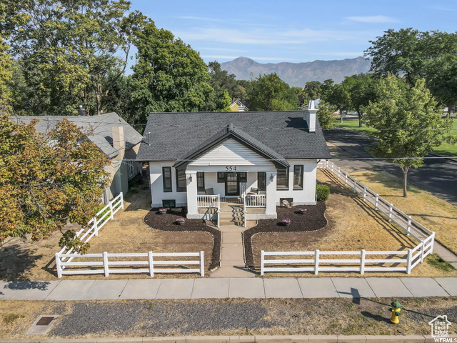 Bungalow-style house featuring a porch, a fenced front yard, a mountain view, and a chimney