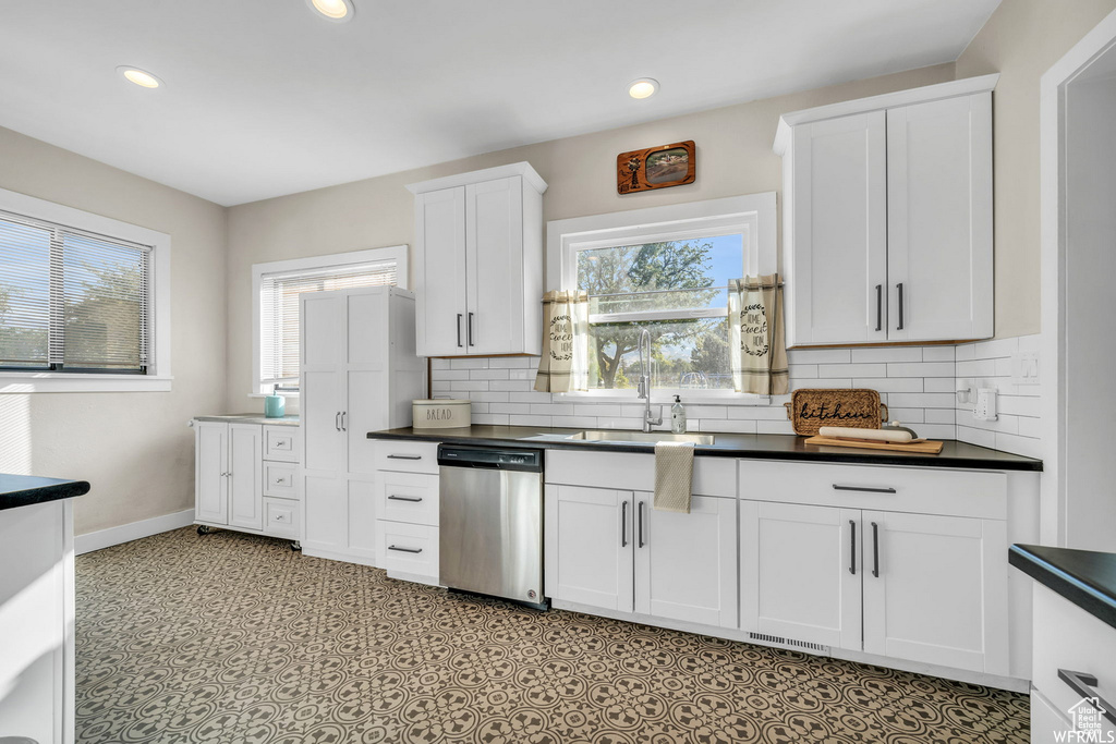 Kitchen featuring stainless steel dishwasher, dark countertops, plenty of natural light, decorative backsplash, and recessed lighting