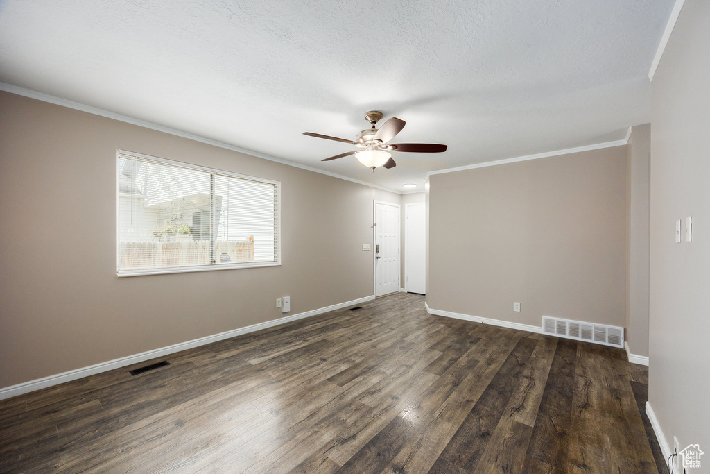 Spare room with crown molding, a ceiling fan, and dark wood-type flooring