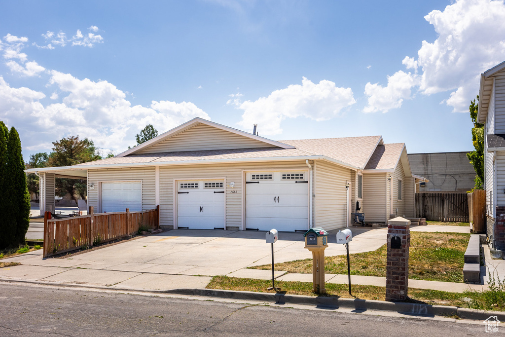 Ranch-style house featuring an attached garage, driveway, and roof with shingles