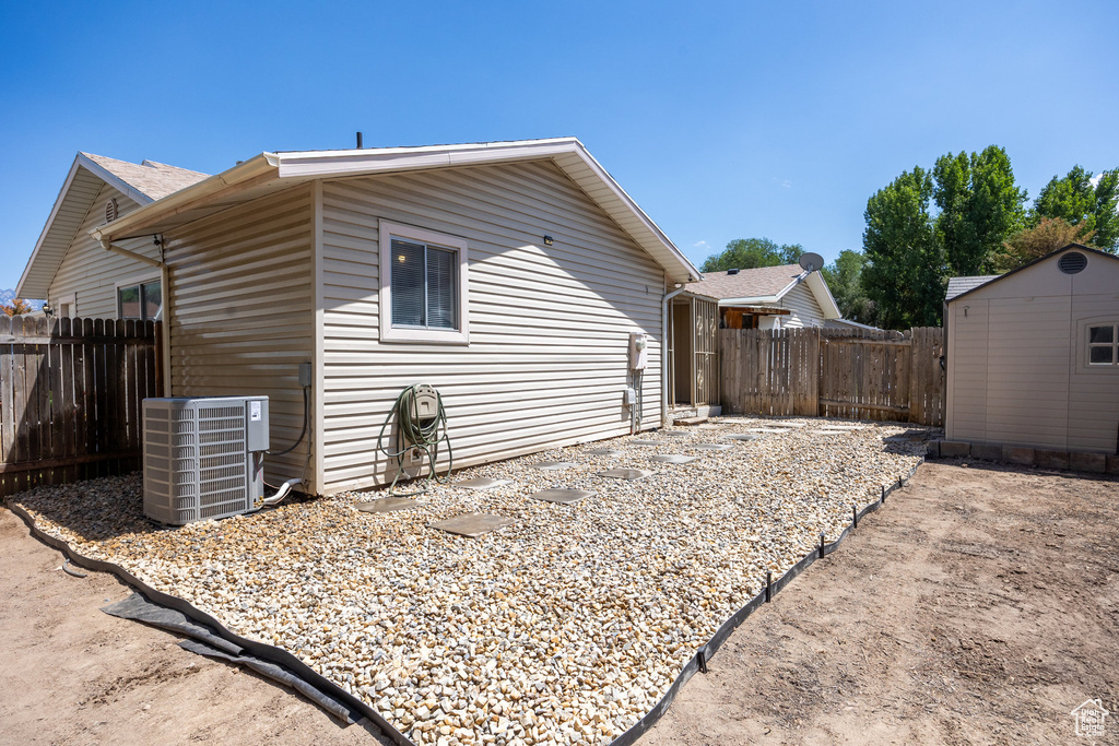 View of side of home with a fenced backyard and a shed