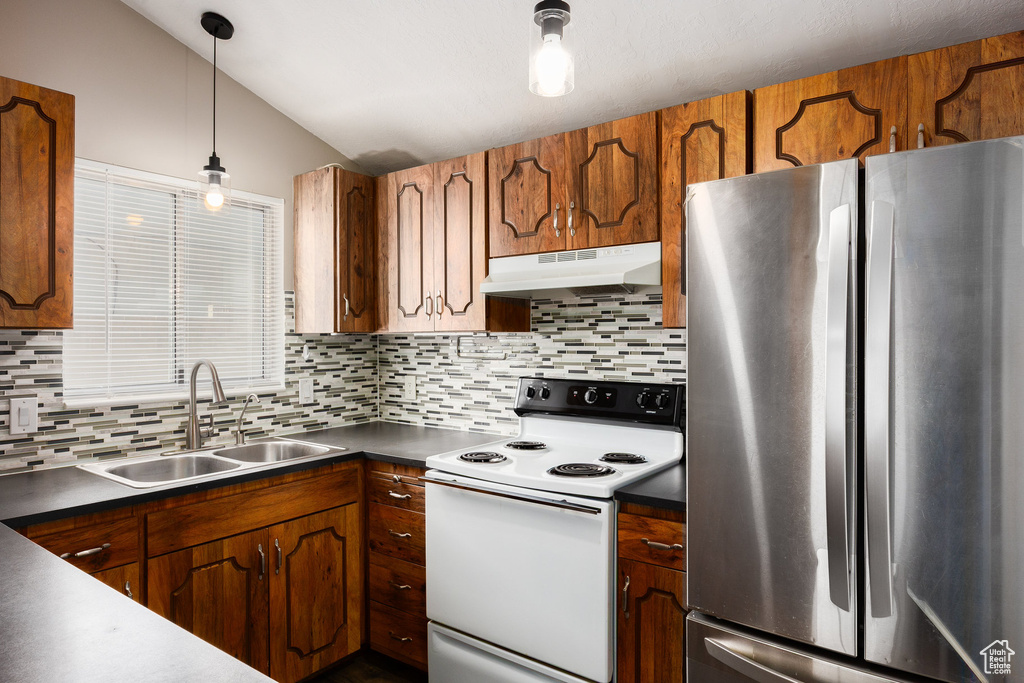 Kitchen featuring freestanding refrigerator, under cabinet range hood, white electric range oven, dark countertops, and tasteful backsplash