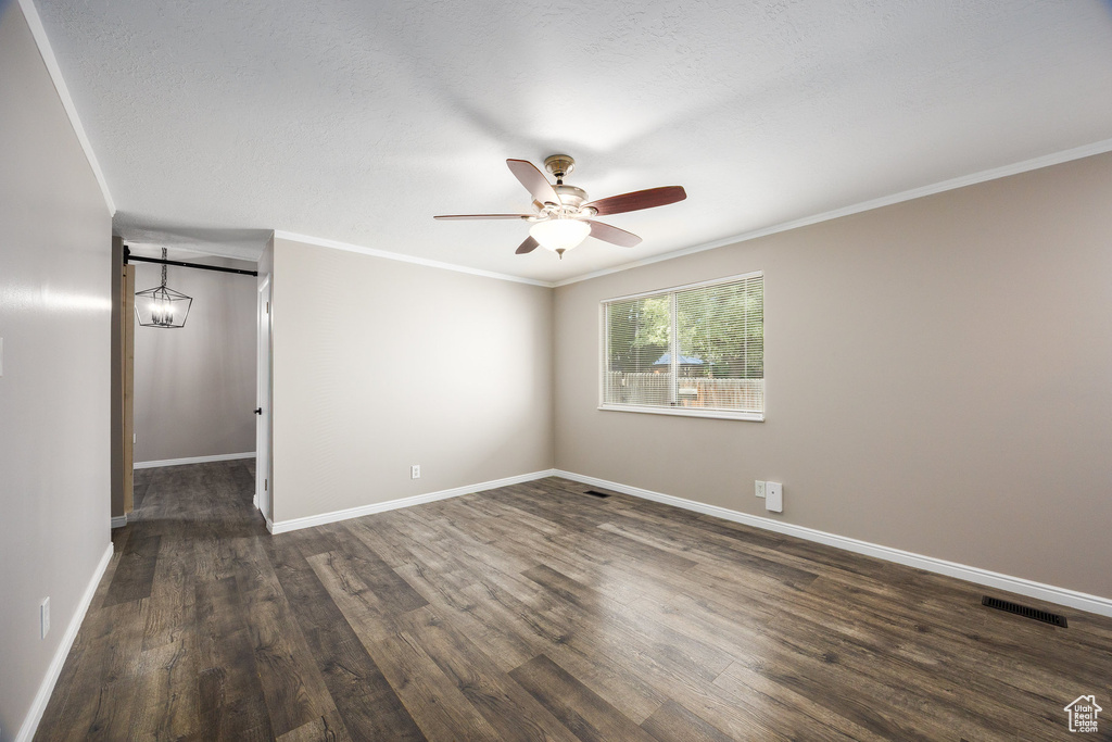 Spare room with ceiling fan, dark wood-type flooring, and ornamental molding