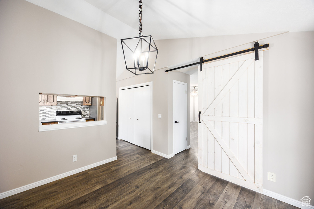 Unfurnished dining area with a barn door, a chandelier, and dark wood-style floors