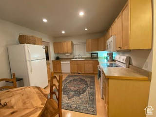 Kitchen featuring white appliances, recessed lighting, light wood-type flooring, and light brown cabinets