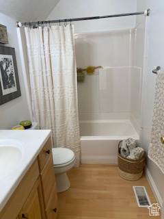 Full bathroom featuring vanity, wood finished floors, shower / tub combo, and vaulted ceiling