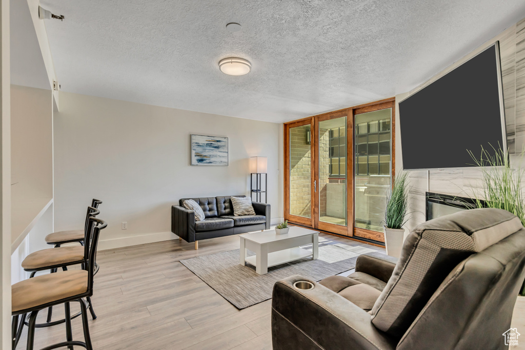 Living room with floor to ceiling windows, light wood-type flooring, and a textured ceiling