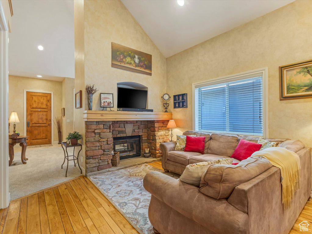 Living area with wood-type flooring, high vaulted ceiling, and a fireplace