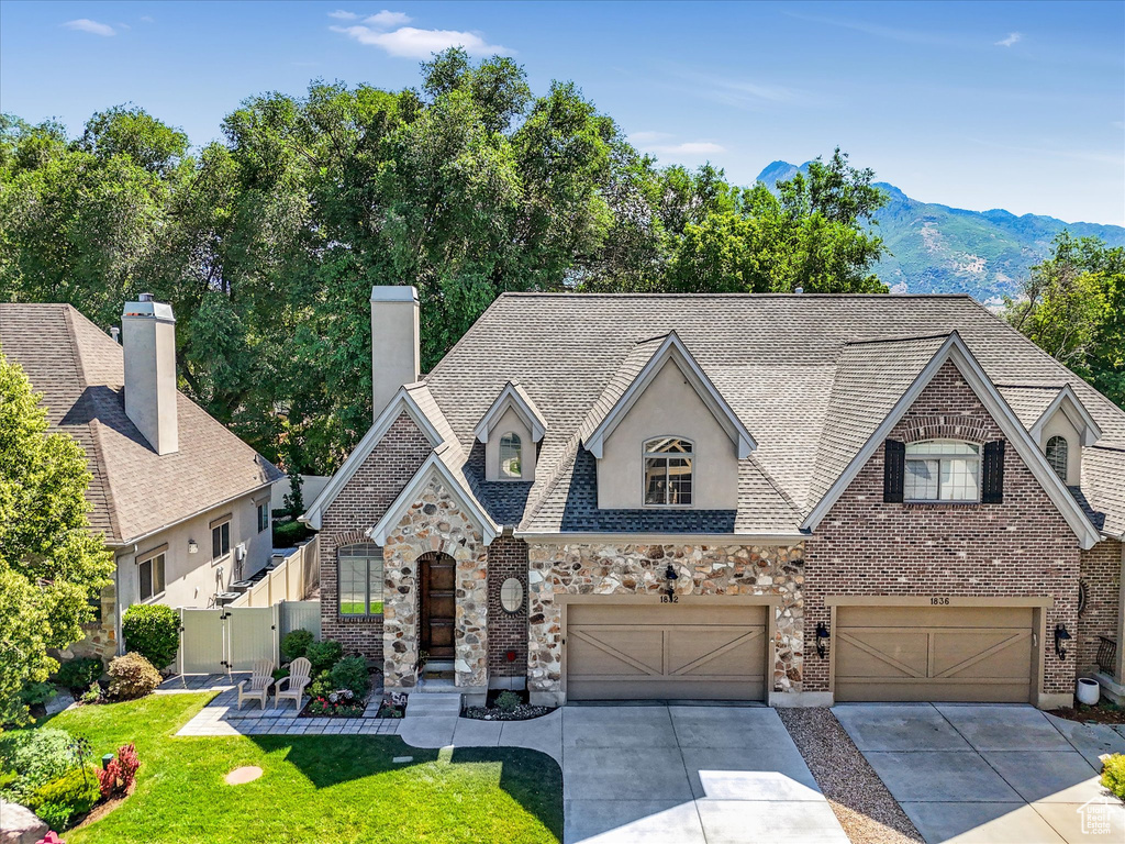 French country inspired facade with driveway, a garage, a gate, and stone siding