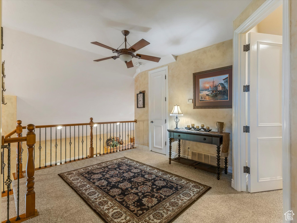 Sitting room with ceiling fan, carpet flooring, and vaulted ceiling