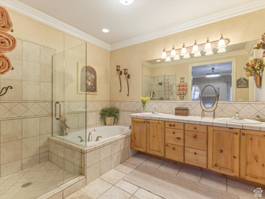 Full bathroom with tile patterned floors, a shower stall, double vanity, a garden tub, and ornamental molding
