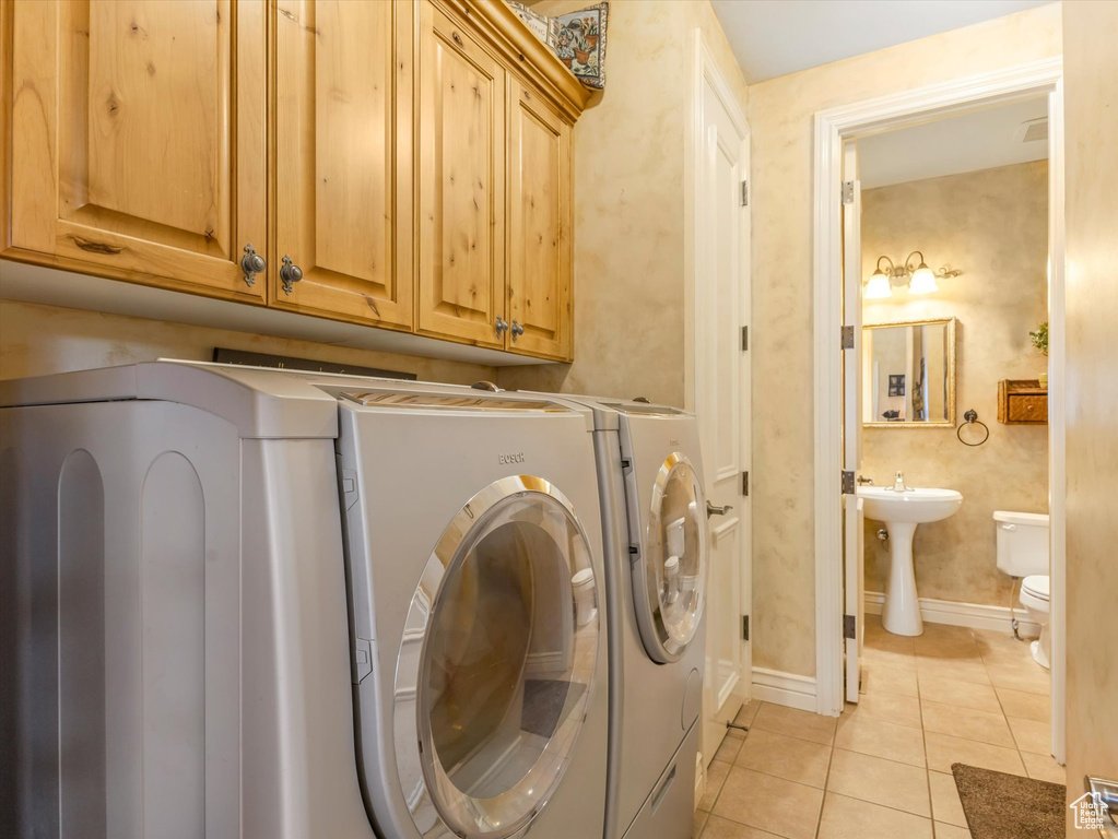 Laundry room with independent washer and dryer, light tile patterned flooring, and cabinet space