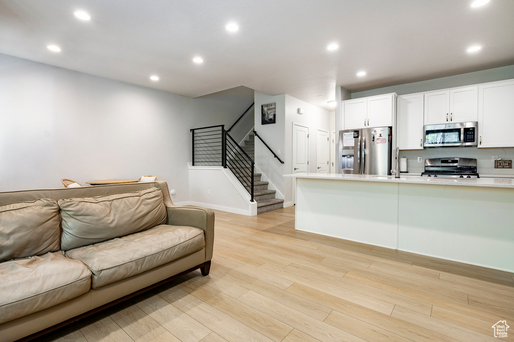 Living room featuring stairs, light wood-style floors, and recessed lighting