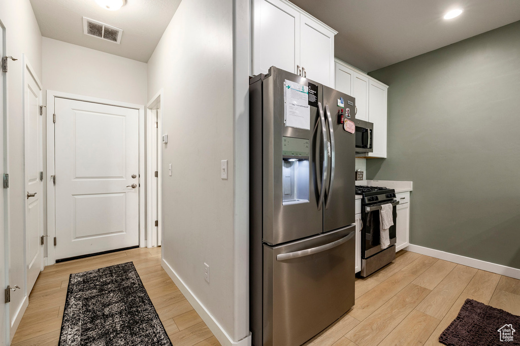 Kitchen featuring stainless steel appliances, light wood finished floors, white cabinetry, and recessed lighting