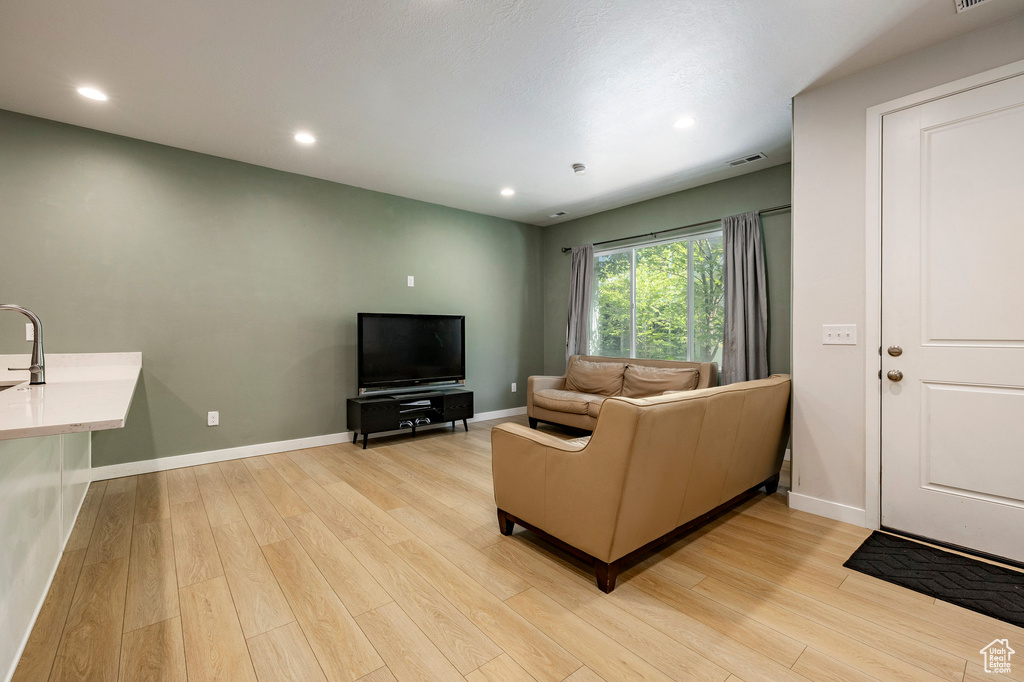 Living area with light wood-style floors and recessed lighting