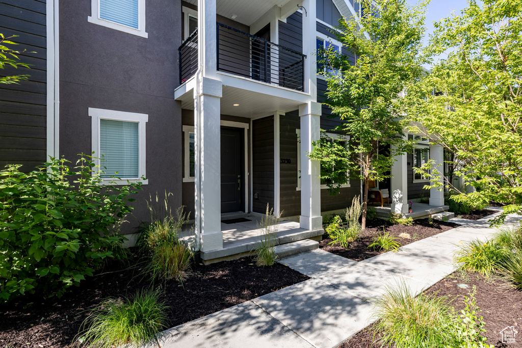 Entrance to property featuring a balcony, a porch, and stucco siding
