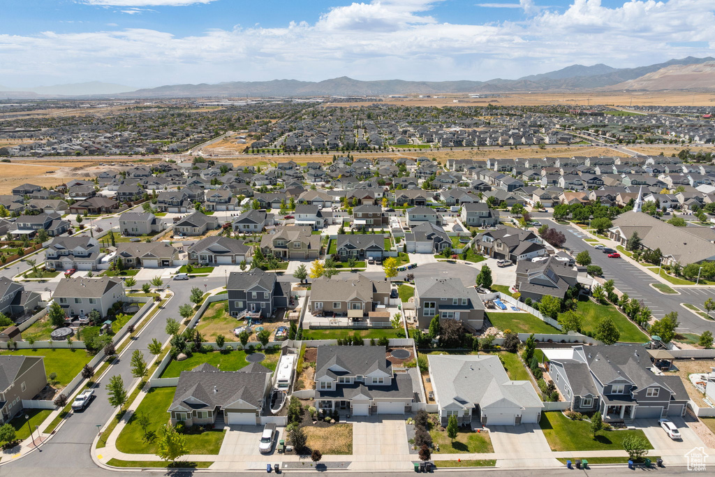 Aerial view of property and surrounding area featuring a mountainous background and nearby suburban area