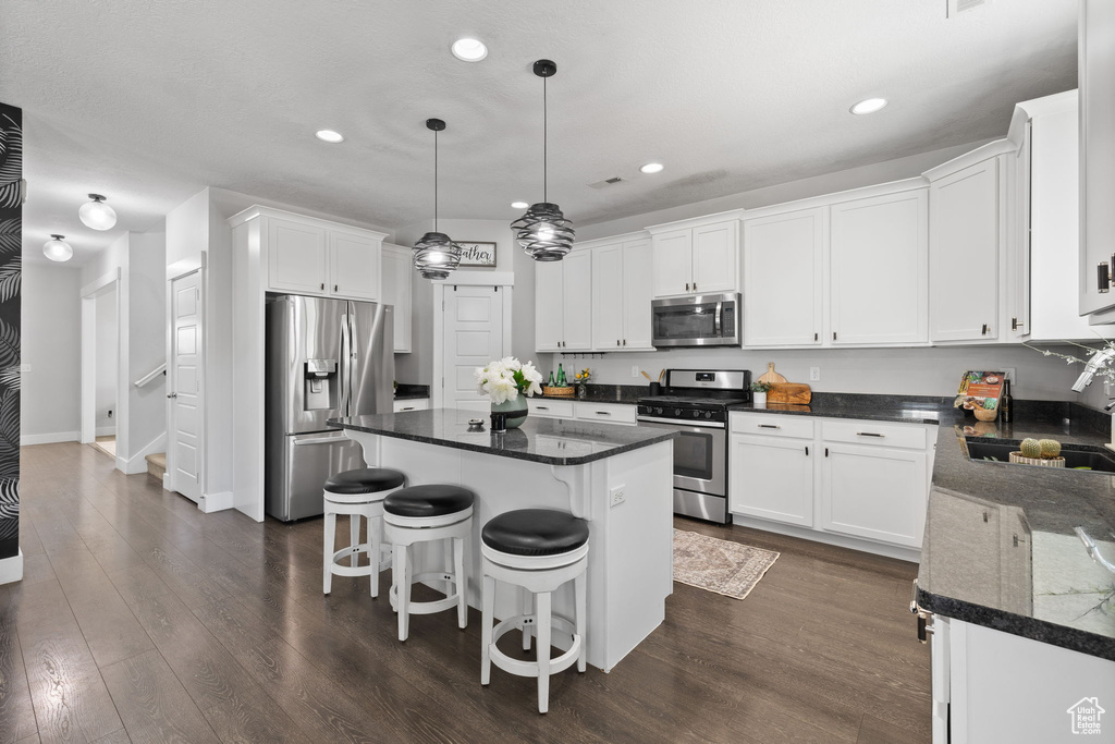 Kitchen featuring stainless steel appliances, recessed lighting, white cabinetry, and a center island