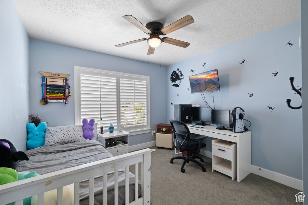 Bedroom featuring an office area, carpet flooring, a textured ceiling, and ceiling fan