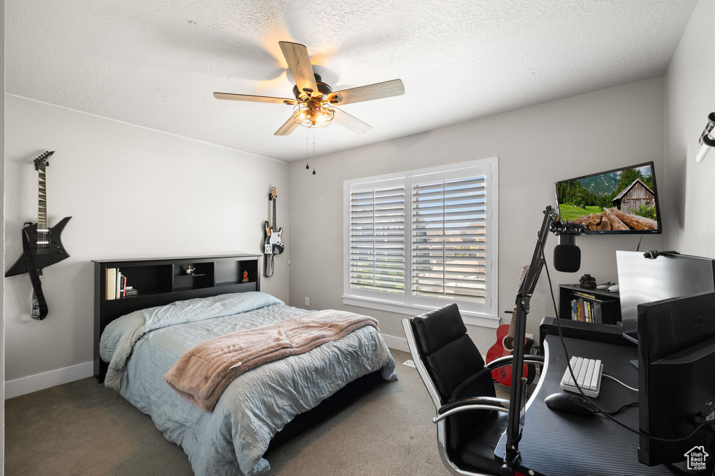 Carpeted bedroom with a desk and a ceiling fan