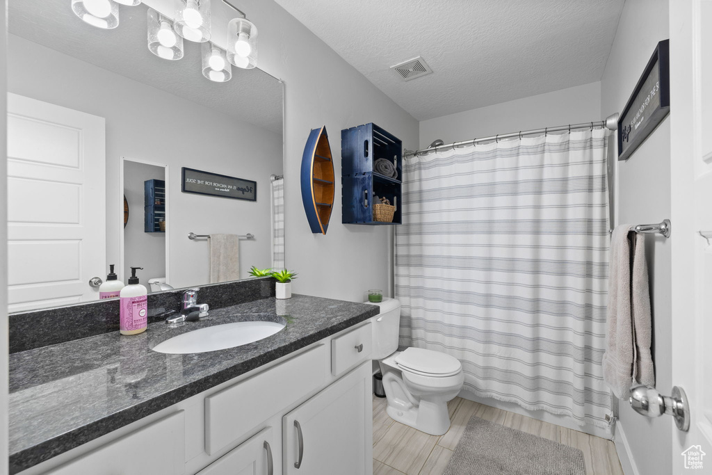 Bathroom with vanity, a shower with shower curtain, a textured ceiling, and wood finished floors