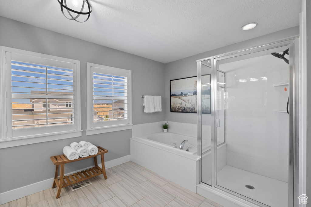 Bathroom featuring a shower stall, a garden tub, and a textured ceiling