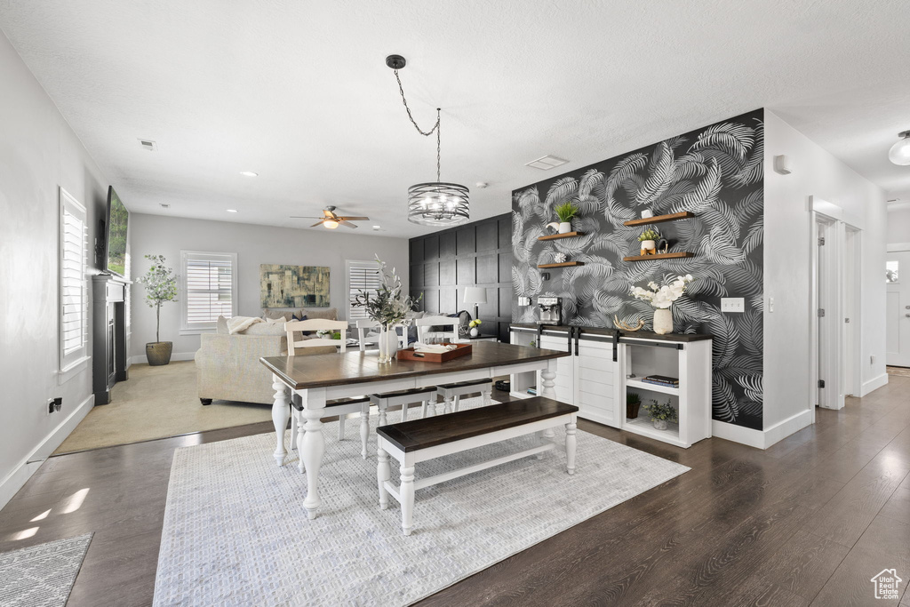 Dining area with a ceiling fan, wood finished floors, a chandelier, and a fireplace