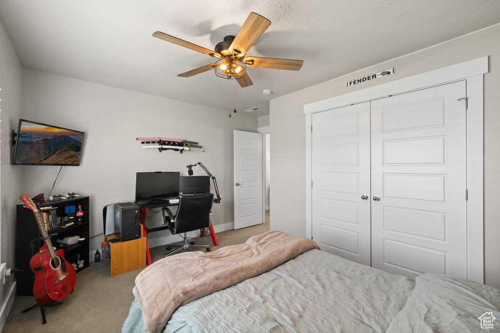 Carpeted bedroom featuring a desk, a closet, and ceiling fan