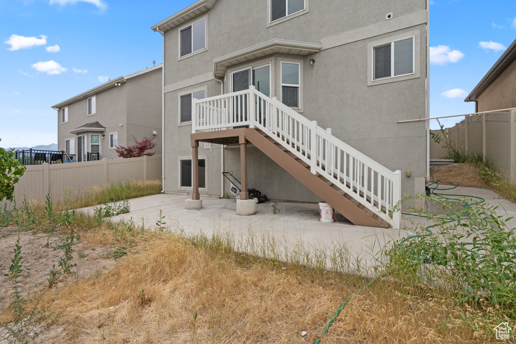 Rear view of property with a patio area, stucco siding, and stairway