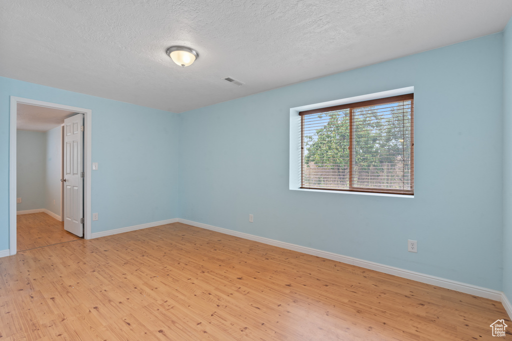 Spare room featuring light wood-type flooring and a textured ceiling