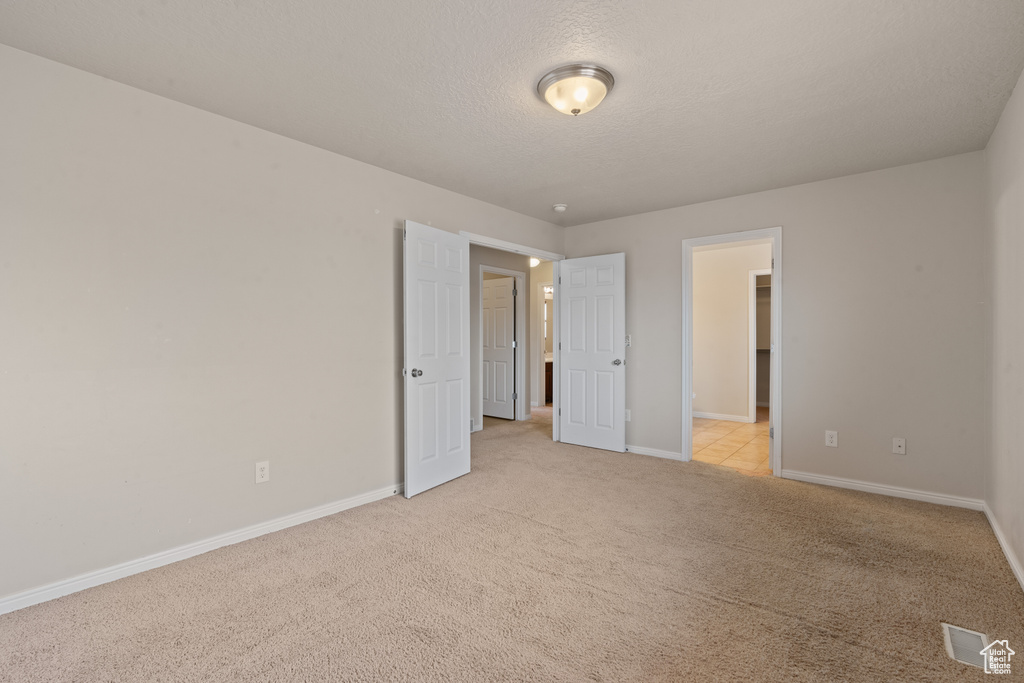 Unfurnished bedroom featuring light carpet and a textured ceiling