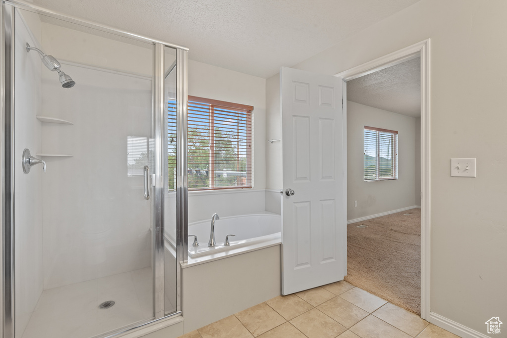 Full bathroom with tile patterned flooring, a textured ceiling, a stall shower, and a bath