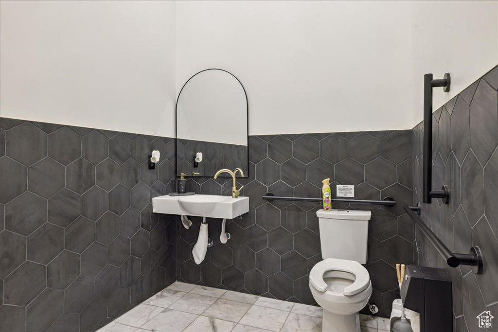 Bathroom with tile walls, a wainscoted wall, and marble finish flooring