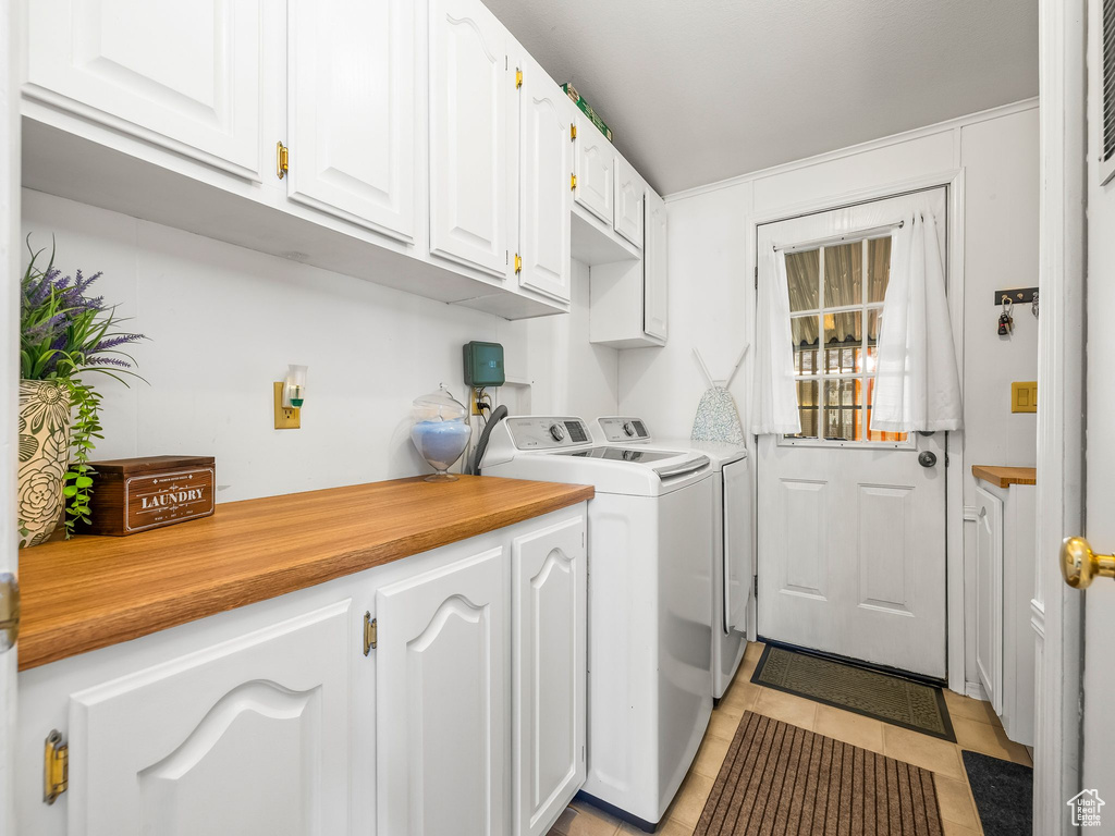 Washroom with cabinet space, washer and clothes dryer, and light tile patterned floors