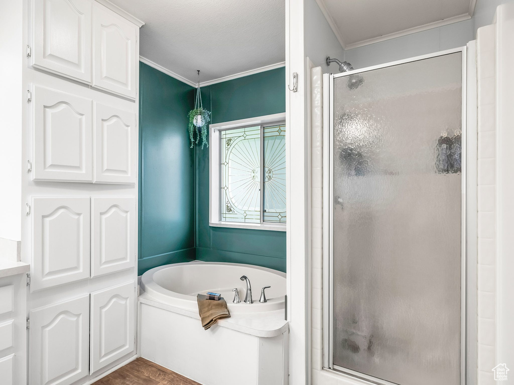 Bathroom featuring a shower stall, a garden tub, ornamental molding, and wood finished floors