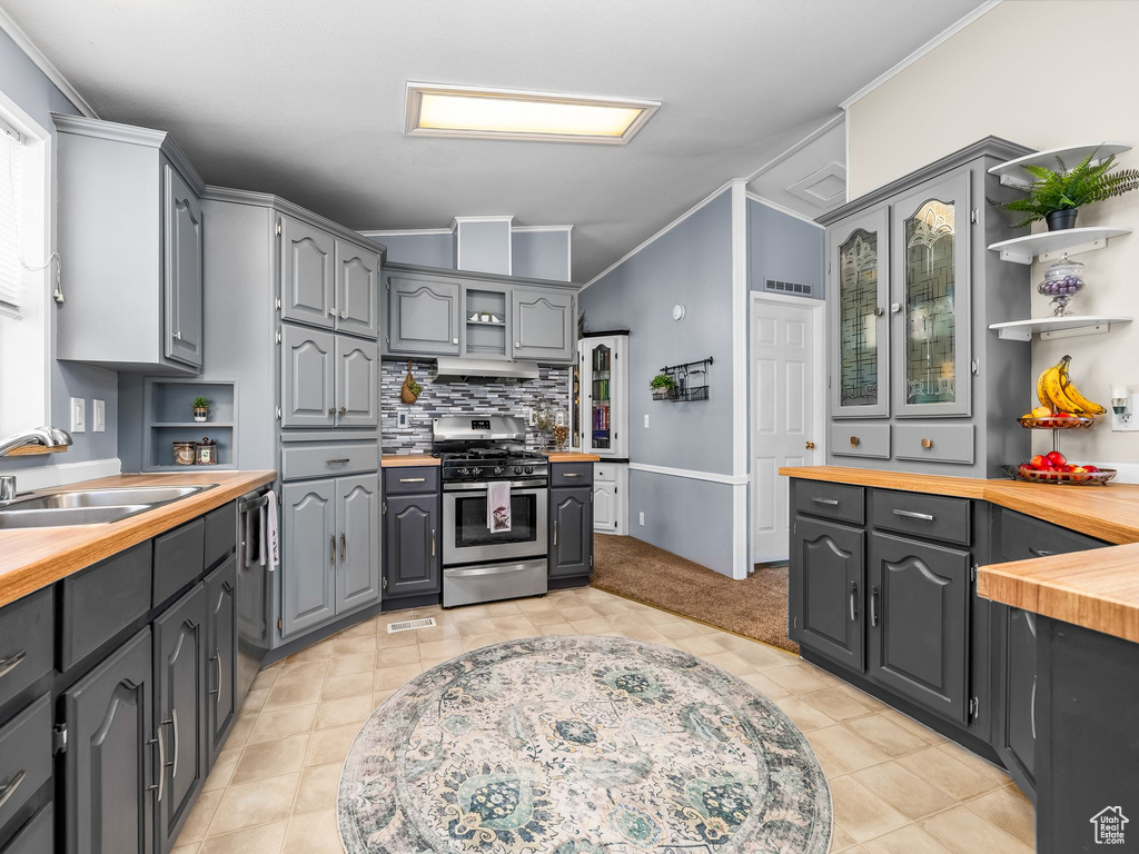 Kitchen with gas range, open shelves, butcher block countertops, dishwasher, and gray cabinetry