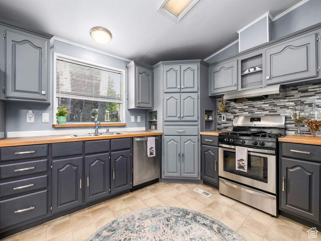 Kitchen featuring stainless steel appliances, wooden counters, ornamental molding, backsplash, and open shelves