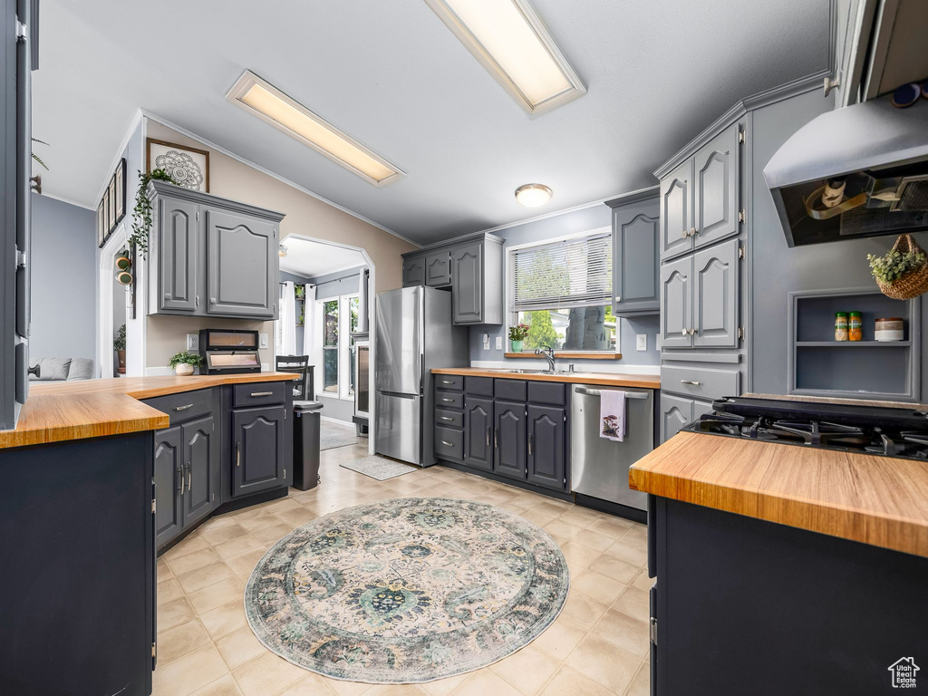 Kitchen featuring wood counters, appliances with stainless steel finishes, vaulted ceiling, under cabinet range hood, and gray cabinets