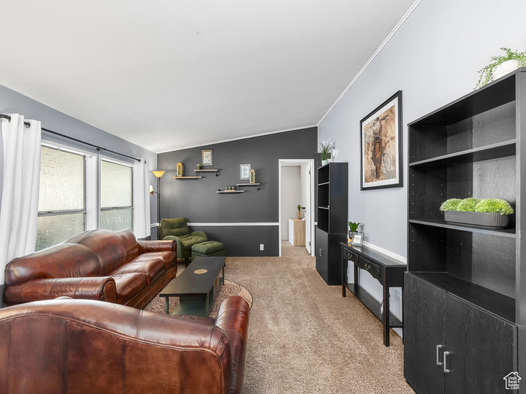 Carpeted living area with crown molding and lofted ceiling