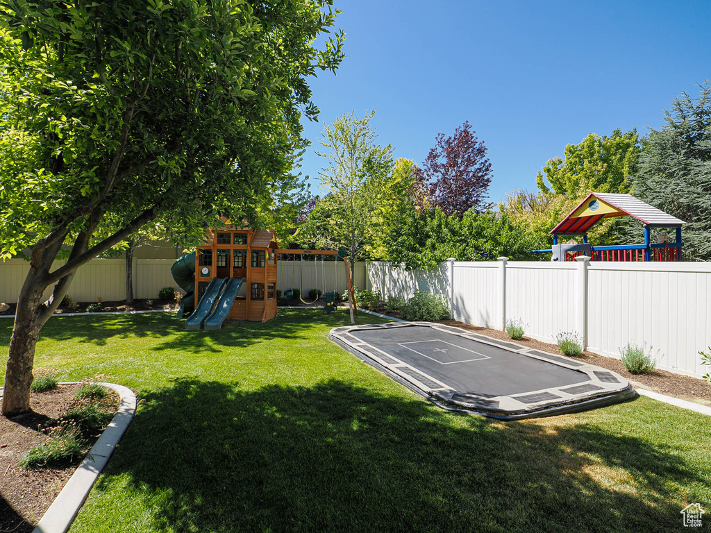 Fenced backyard featuring a playground