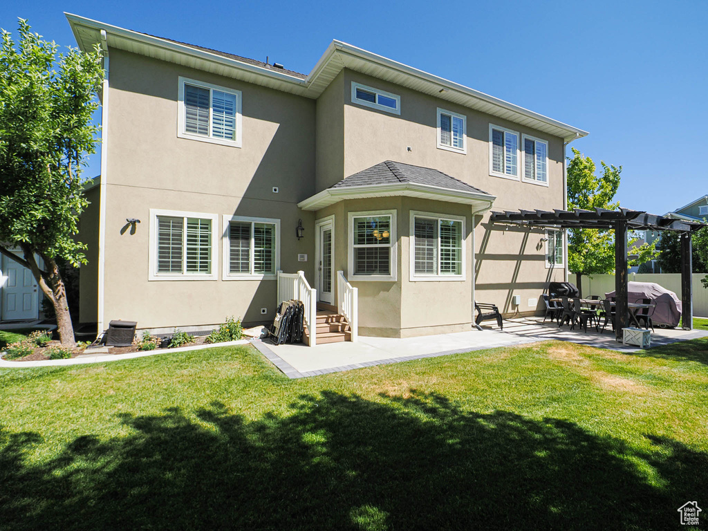 Rear view of house with stucco siding, a pergola, and a patio area