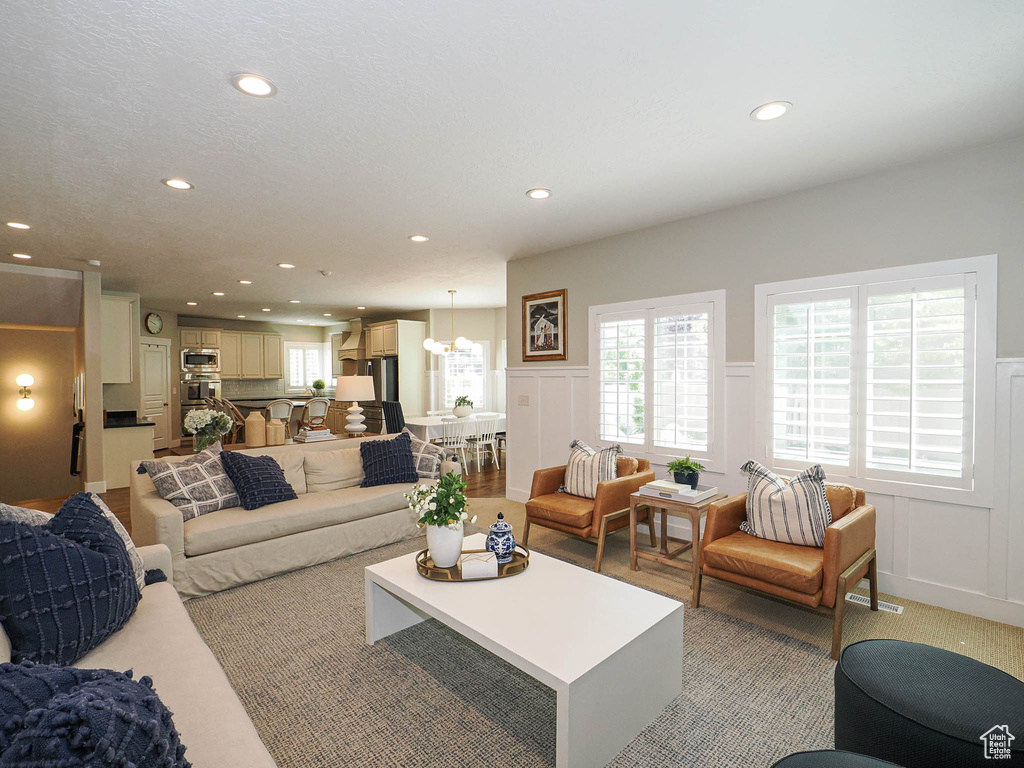 Living room with a decorative wall, recessed lighting, wainscoting, and light carpet