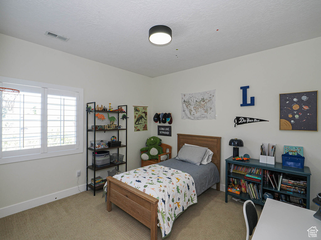 Bedroom with light carpet and a textured ceiling