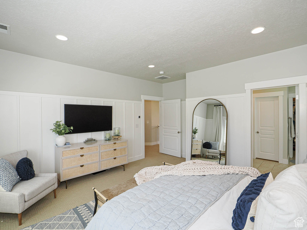 Bedroom with a textured ceiling, recessed lighting, light carpet, arched walkways, and a closet