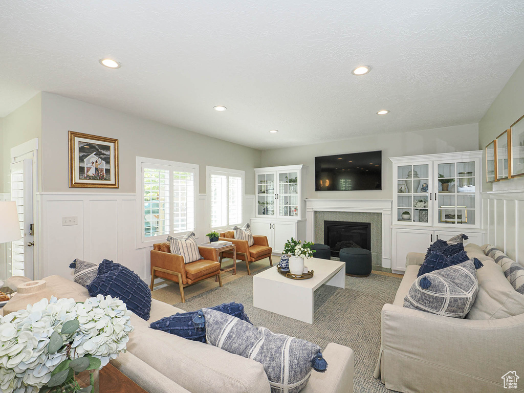 Living area featuring a decorative wall, a wainscoted wall, a glass covered fireplace, and recessed lighting