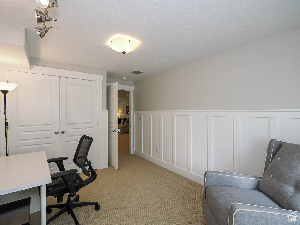 Office featuring light colored carpet, a decorative wall, and a wainscoted wall