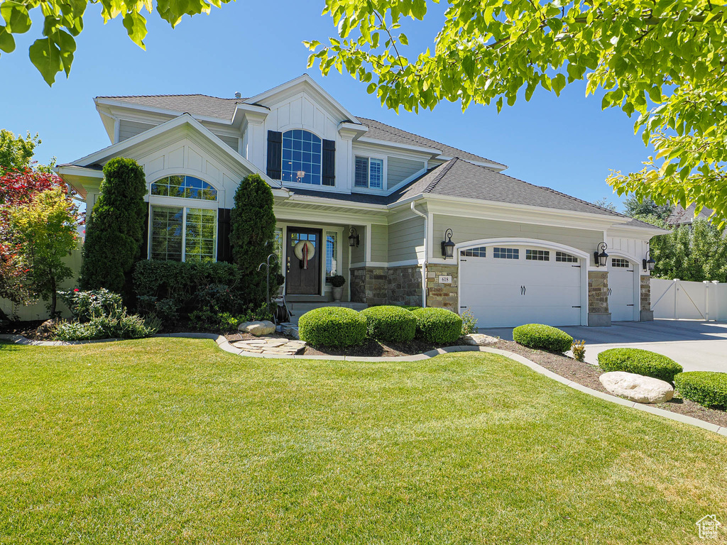 View of front of house featuring an attached garage, stone siding, driveway, and a shingled roof