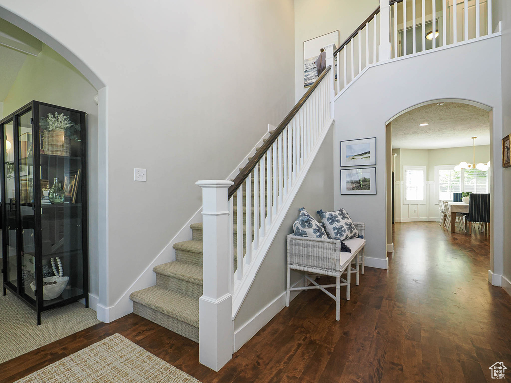 Staircase featuring wood finished floors, arched walkways, and a towering ceiling